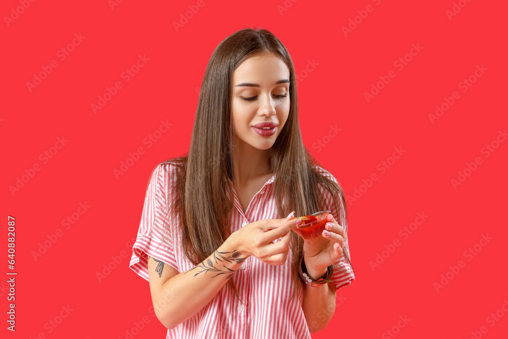 Beautiful happy young woman eating french fries with ketchup on red background