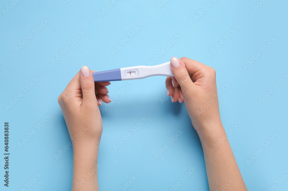 Female hands with negative pregnancy test on color background