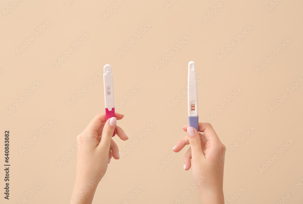 Female hands with pregnancy tests on color background