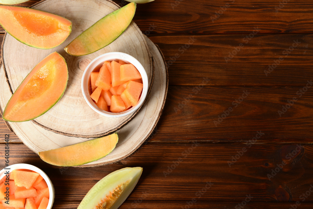 Board and bowls with pieces of sweet melon on wooden table