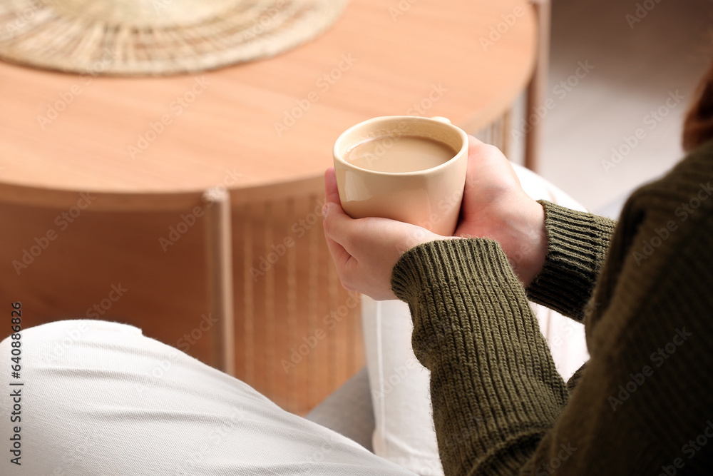 Woman with cup of tasty coffee at home, closeup