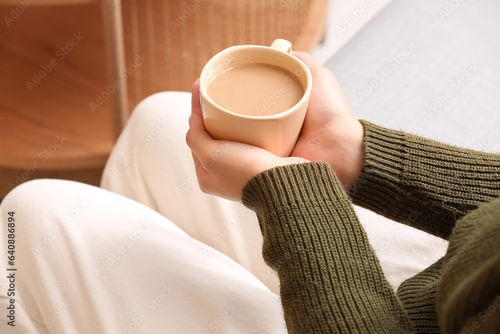 Woman with cup of tasty coffee at home, closeup