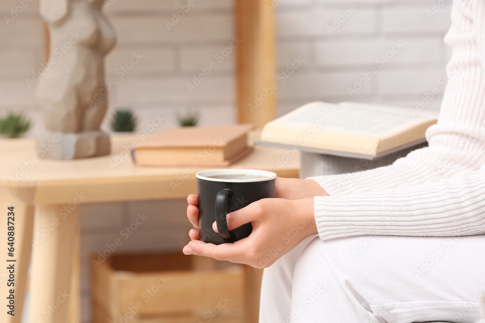 Woman holding cup of tasty coffee at home, closeup