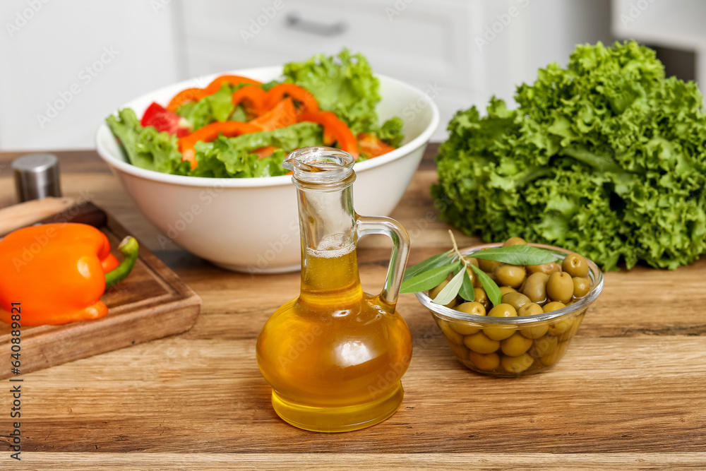 Jug with oil and olives on table in kitchen