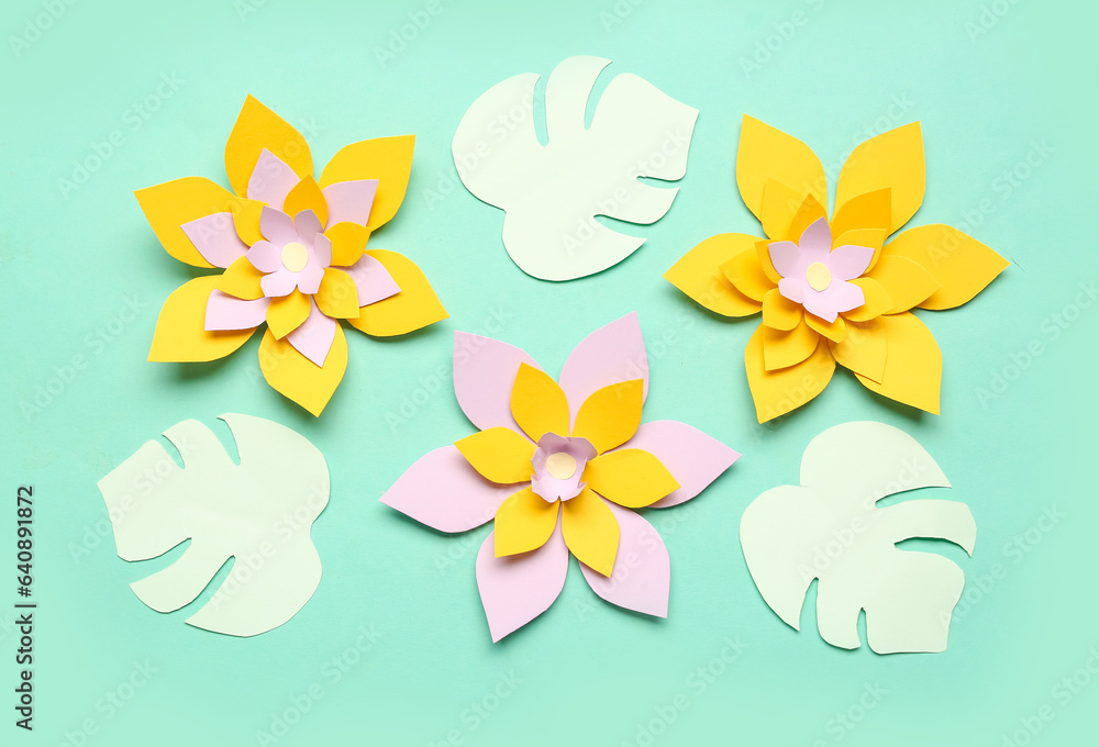 Colorful origami flowers with leaves on green background