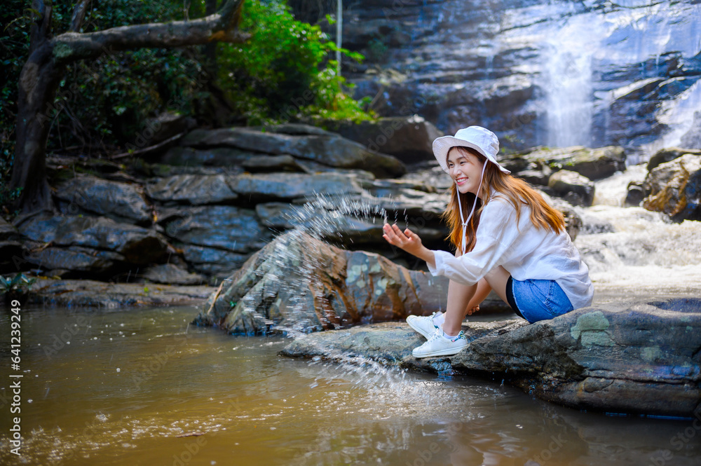 asian woman traveller relaxing in deep tropical jungle waterfall 