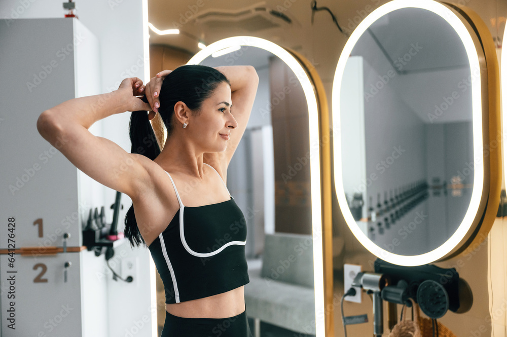 Woman is taking care of her hair in the changing room