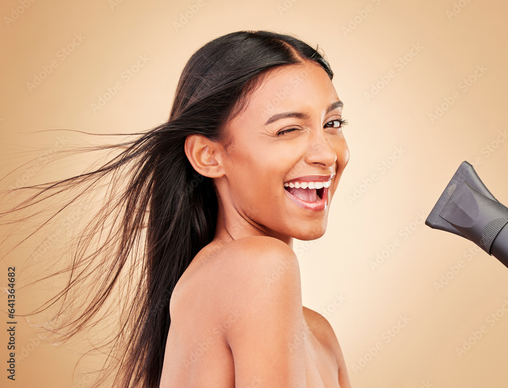 Wink, hair and portrait of happy woman with hairdryer for beauty isolated in a studio brown backgrou