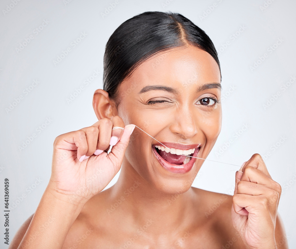 Woman, portrait and wink to floss teeth in studio for healthy dental care, gum gingivitis or plaque 