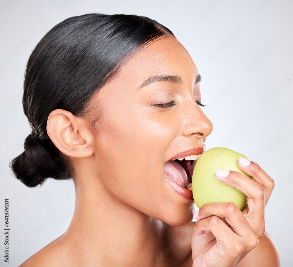 Face, beauty and woman biting an apple for health, wellness or nutrition in studio on white backgrou