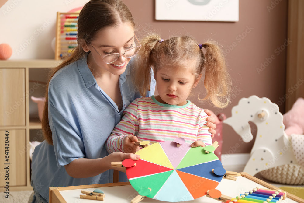 Mother and her little daughter playing matching game with clothespins at home