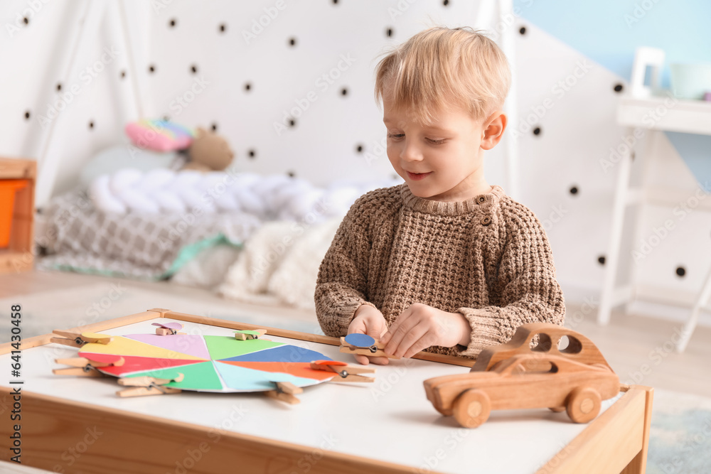 Cute little boy playing matching game with clothespins at home