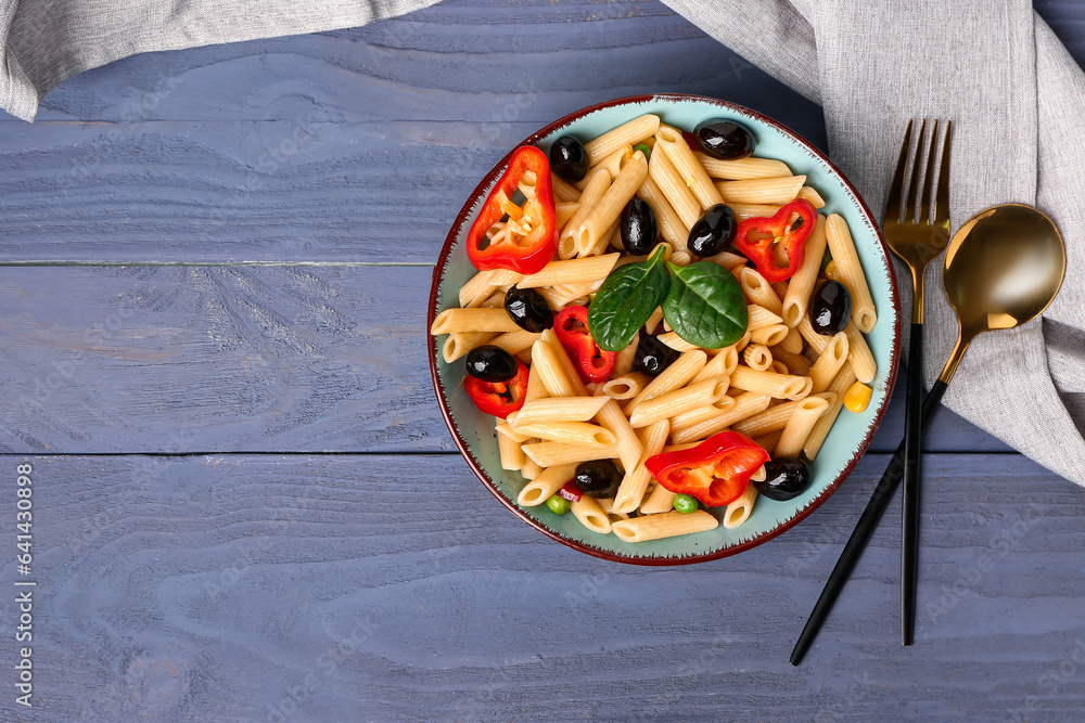 Bowl with tasty pasta salad on blue wooden background