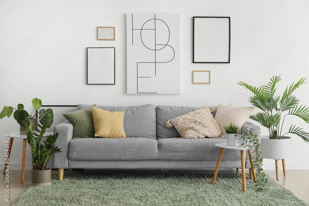 Interior of living room with cozy sofa, paintings and houseplants