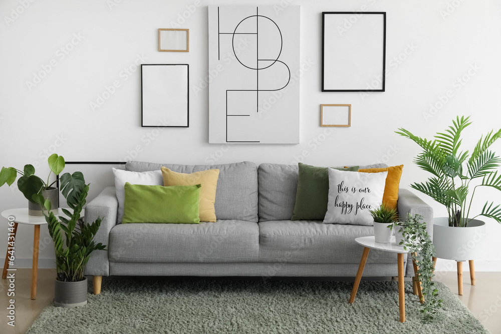 Interior of living room with cozy sofa, paintings and houseplants