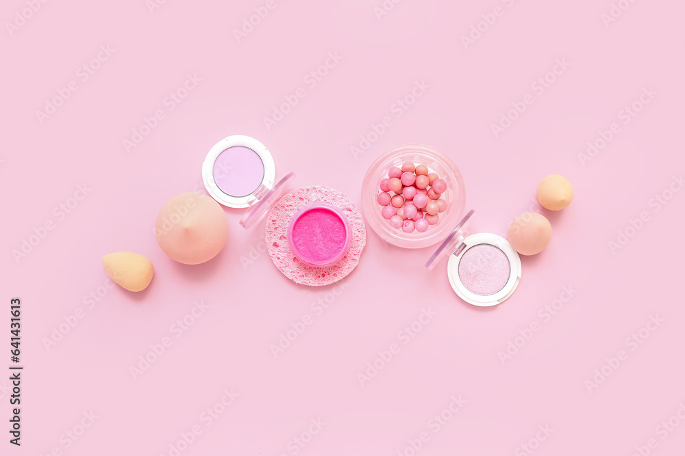 Decorative cosmetics with makeup sponges on pink background