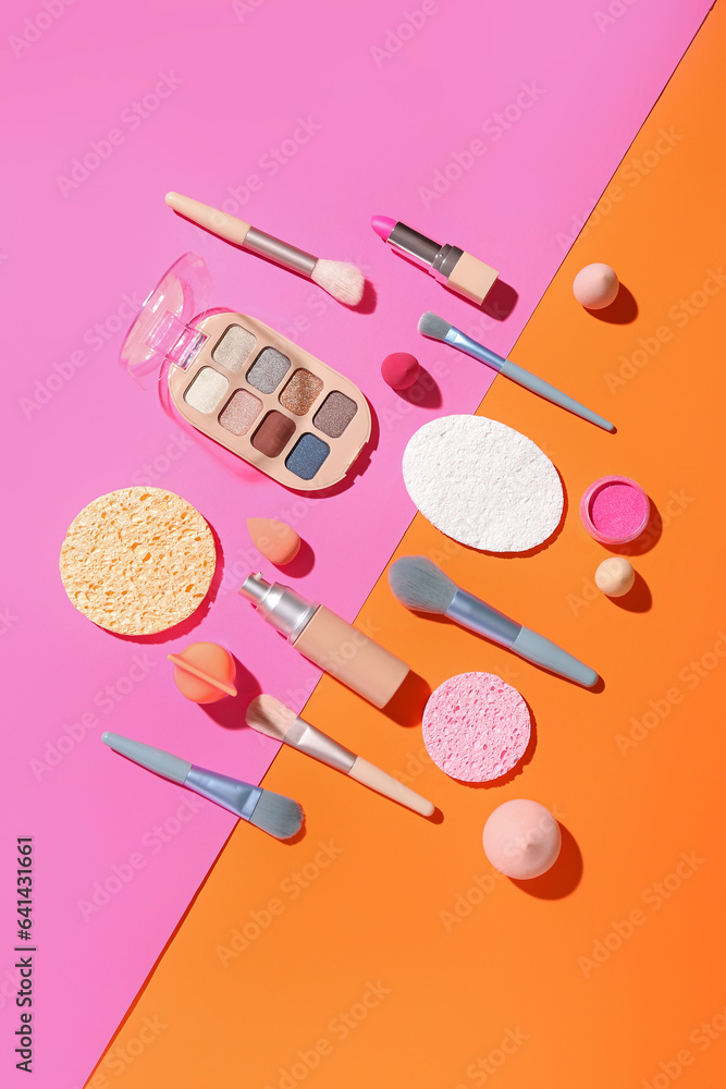 Decorative cosmetics with makeup brushes and sponges on color background