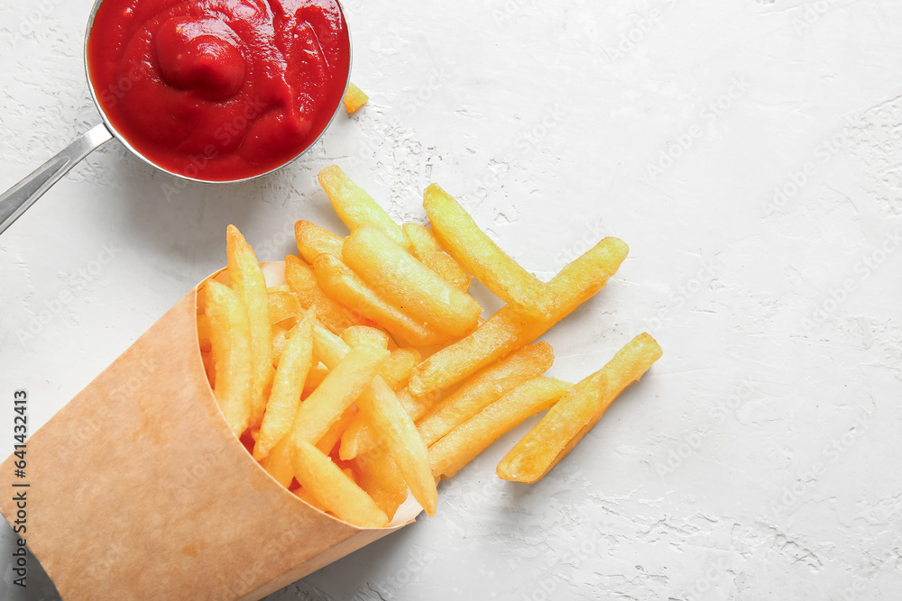 Paper box with tasty french fries and ketchup on light background