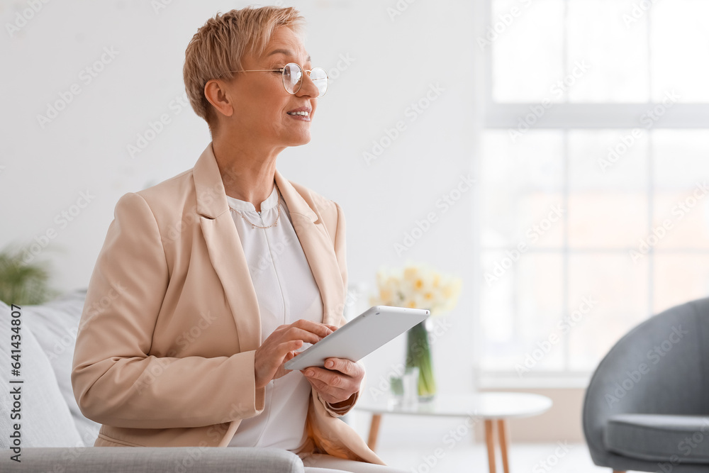 Mature psychologist working with tablet computer in office