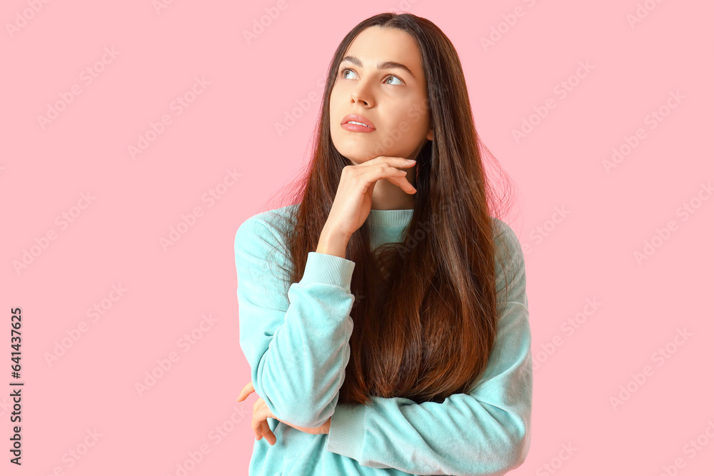 Thoughtful young woman on pink background