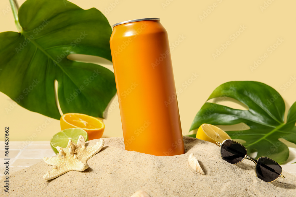 Can of soda with seashells, sunglasses and citrus fruits on sand, closeup