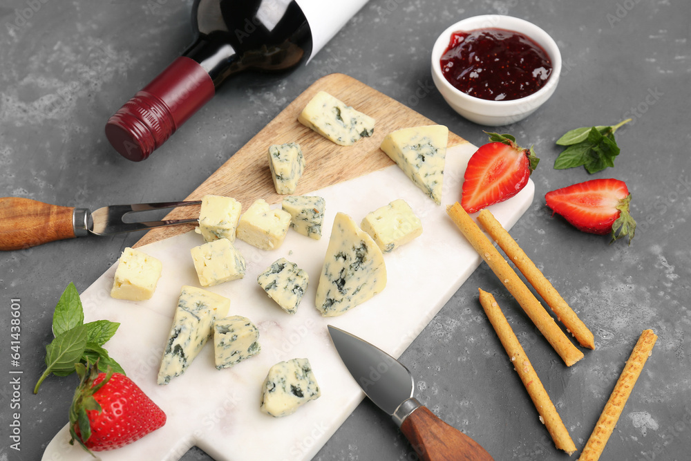 Board with pieces of tasty cheese and sauce on grey background