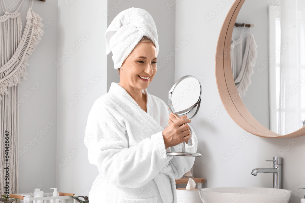 Mature woman with mirror in bathroom