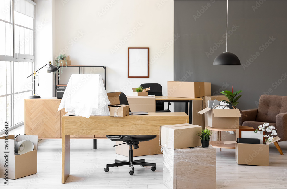 Interior of light office with cardboard boxes on moving day