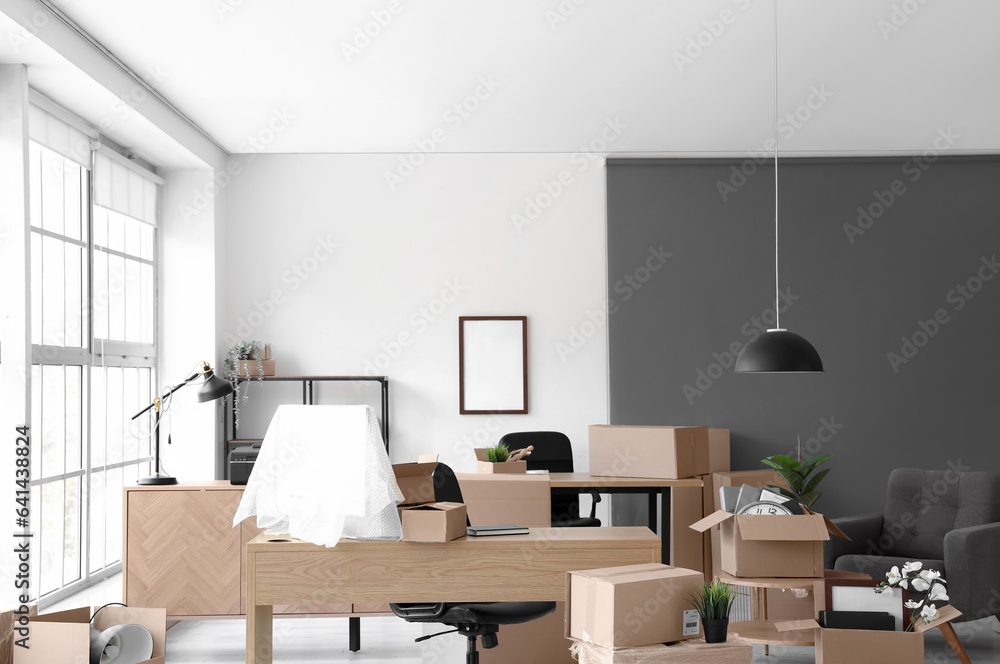 Interior of light office with cardboard boxes on moving day