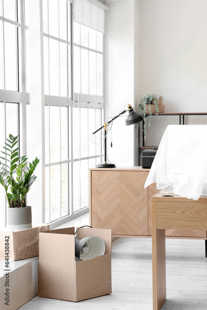 Interior of light office with cardboard boxes on moving day