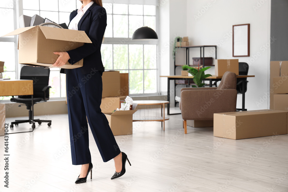 Businesswoman holding cardboard box with personal belongings in office on moving day