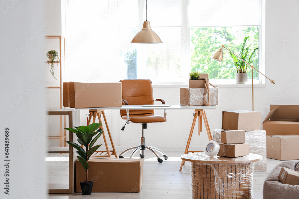 Interior of stylish office with cardboard boxes on moving day