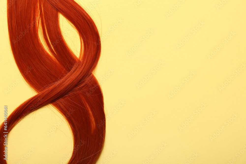 Ginger hair strand on yellow background, closeup