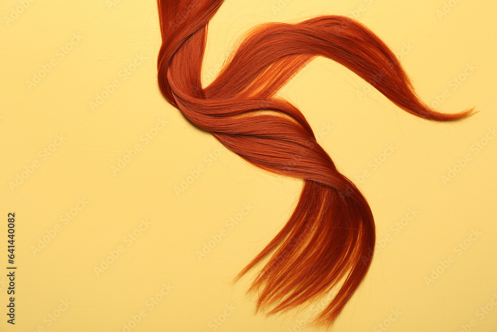 Ginger hair strand on yellow background, closeup