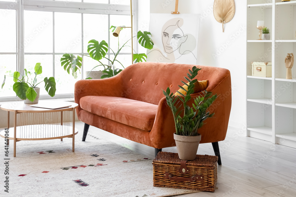 Interior of light living room with cozy brown sofa and coffee table near big window