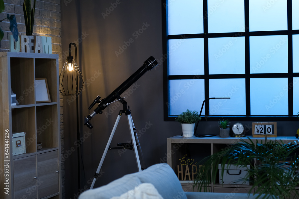 Interior of stylish living room with telescope and shelving unit at night