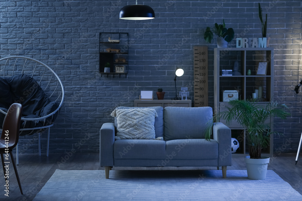 Interior of stylish living room with sofa and shelving unit at night