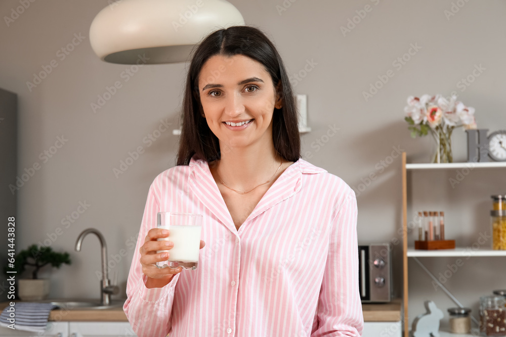 Beautiful woman with glass of fresh milk in kitchen