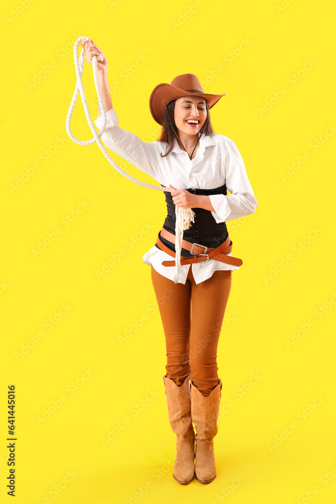 Beautiful cowgirl with lasso on yellow background