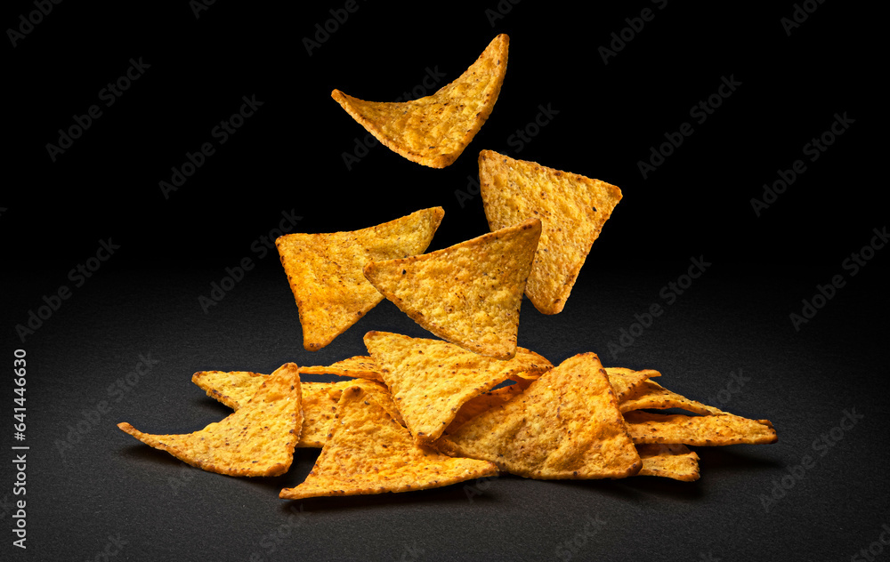 Falling corn chips, hot Mexican nachos isolated on black background