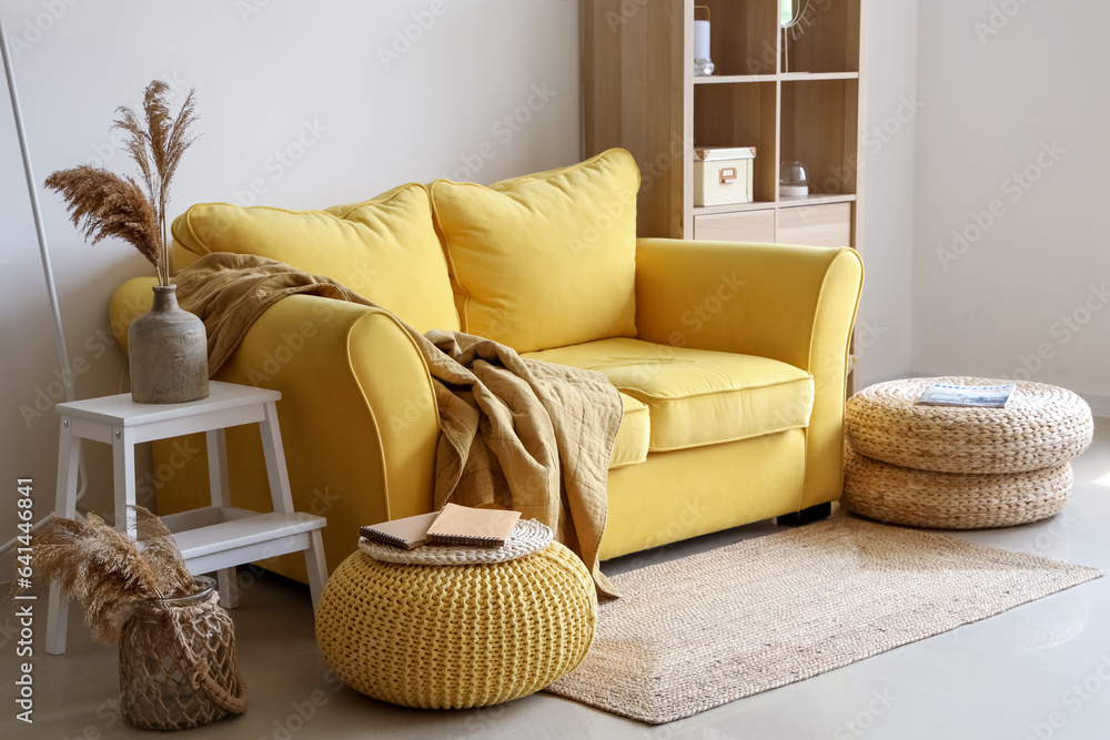 Interior of light living room with stylish yellow sofa and soft poufs