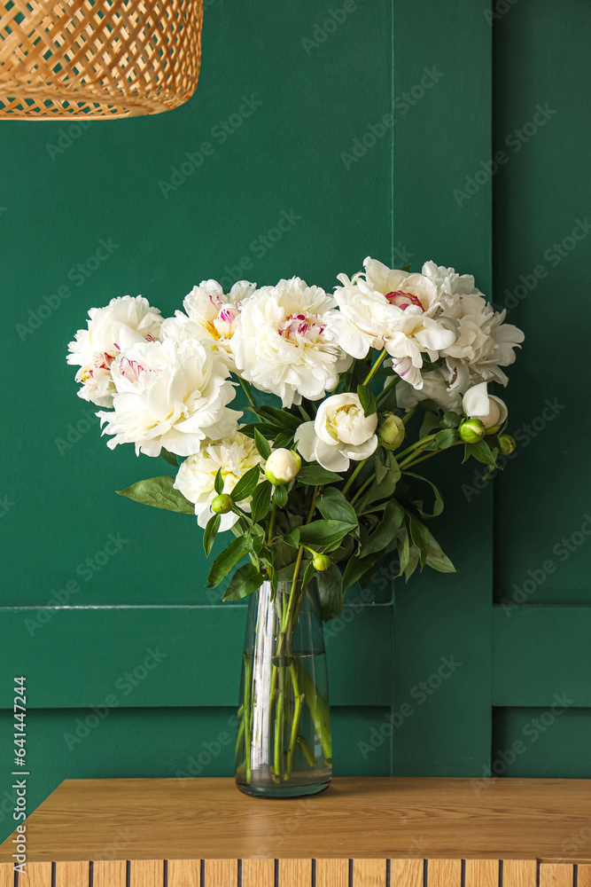 Vase of white peonies on dresser near green wall