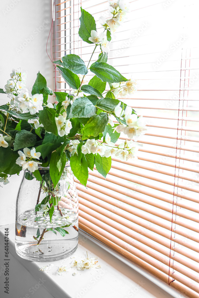 Vase with blooming jasmine flowers on windowsill, closeup