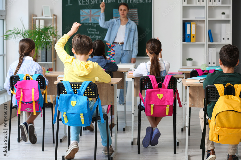 Little pupils with backpacks having lesson in classroom, back view