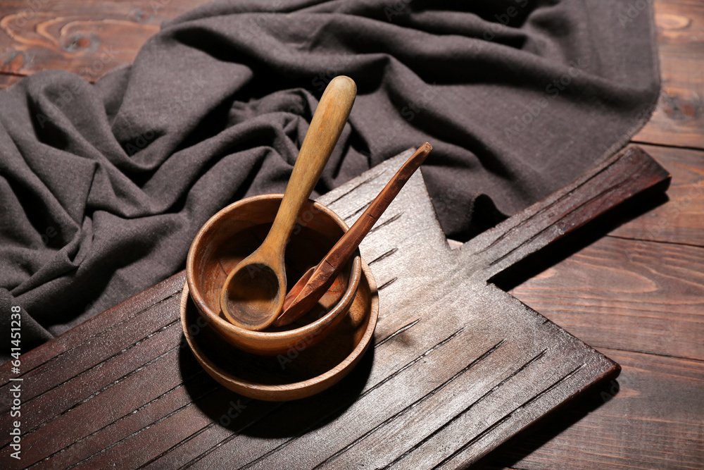 New cutting board, bowls and spoons on wooden background