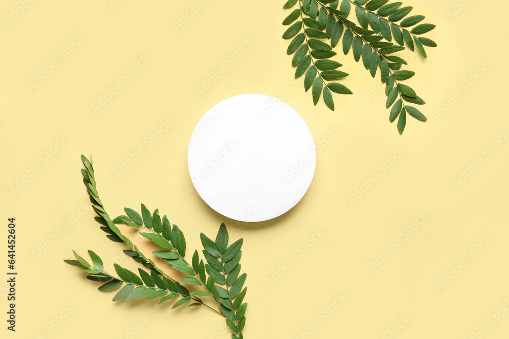 Green leaves of acacia tree with round blank card on beige background