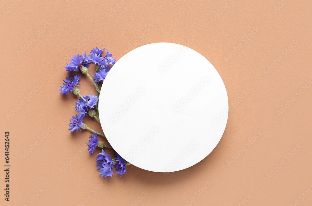 Beautiful cornflowers with round blank card on beige background