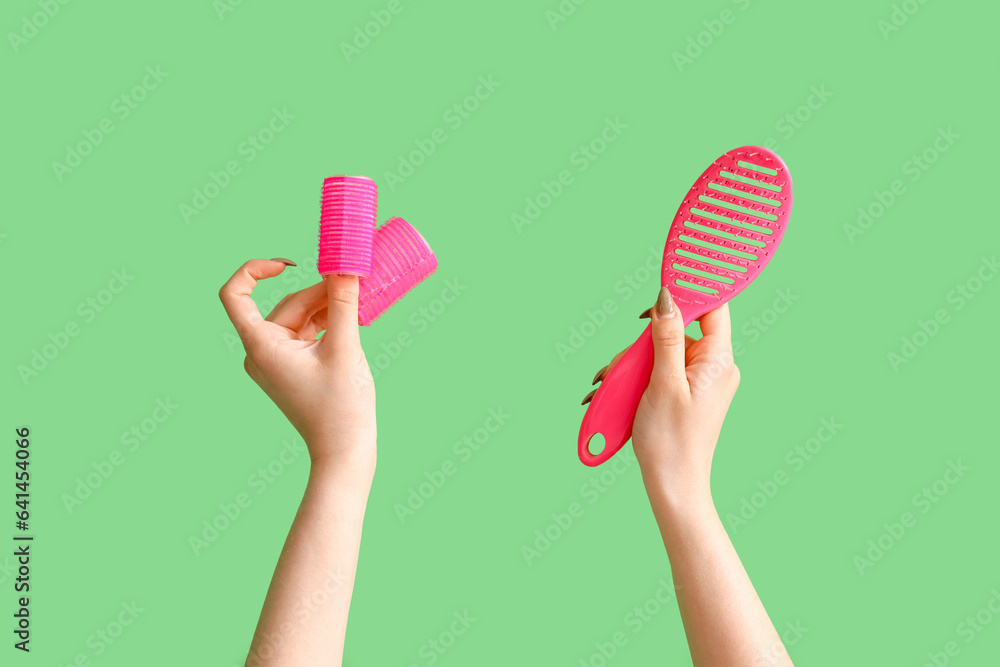 Female hands with brush and curlers on green background