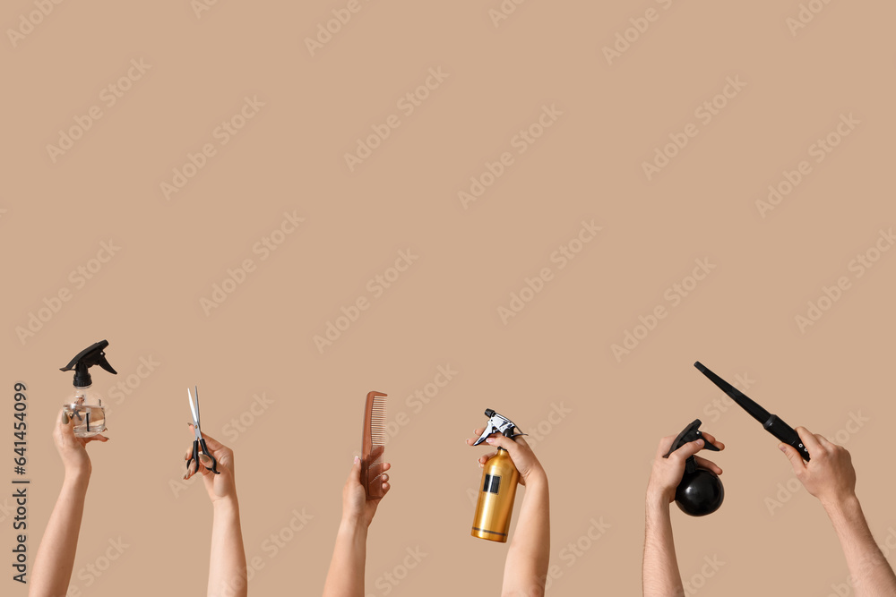 Many hands with different hairdressing supplies on beige background