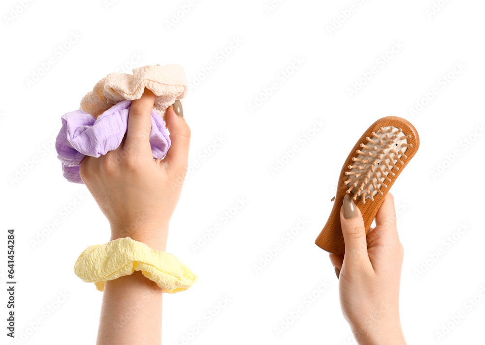 Female hand with different silk scrunchies and brush isolated on white background